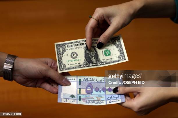 This picture shows two women exchanging a one US dollar bill against a fifty thousand Lebanese pound banknote, in the Lebanese capital Beirut, on...