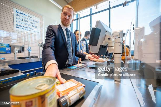 January 2023, Saxony, Görlitz: Michael Kretschmer , Prime Minister of Saxony, stands at the checkout in a Lidl store. The sales collected go to the...