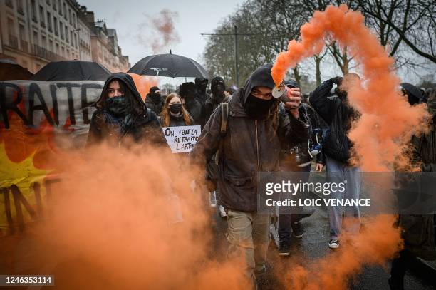 Demonstrator waves a smoke grenade during a rally called by French trade unions in Nantes, western France on January 19 as workers go on strike over...