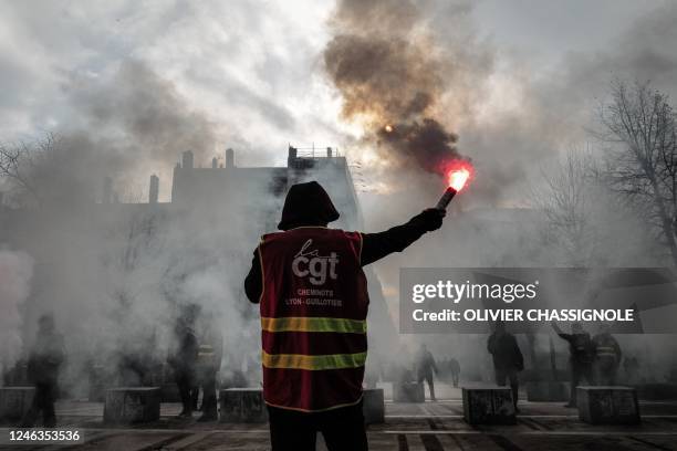 Demonstrator, wearing a jacket of the French union General Confederation of Labour , waves a light flare during a rally in Lyon, south-eastern France...