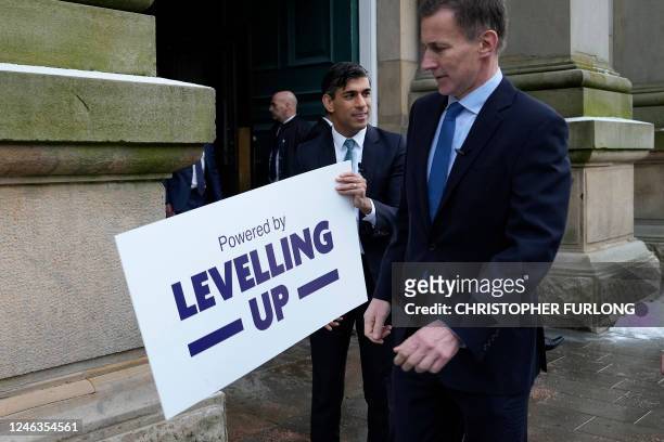 Britain's Prime Minister Rishi Sunak and Chancellor of the Exchequer Jeremy Hunt prepare to attach a "Powered by Levelling Up" plaque during a visit...