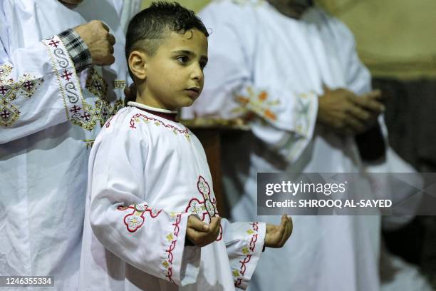 Young deacon prays during the Epiphany eve mass at the cave church in the Coptic Orthodox monastery complex of St. Simon the Tanner, in the eastern...