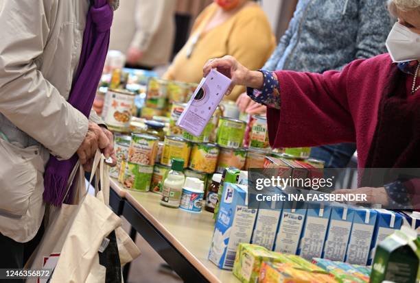 Volunteer puts an item into the bag of a customer at a food bank of the 'Seniorenglueck' association during in Dortmund, western Germany, on January...