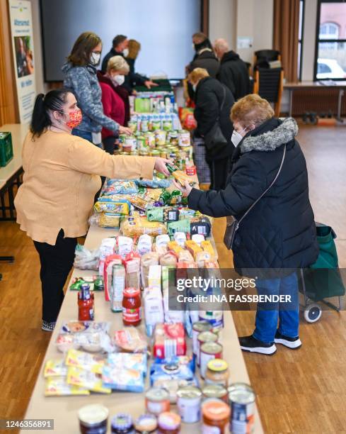 Volunteer hands a package of food to a customer at a food bank of the 'Seniorenglueck' association during in Dortmund, western Germany, on January...