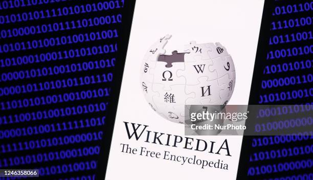 Wikipedia logo displayed on a phone screen and a binary code displayed on a screen are seen in this illustration photo taken in Krakow, Poland on...