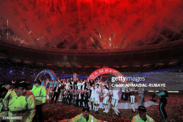 Iraq's national football team players celebrate with the trophy on the podium after winning the 25th Arabian Gulf Cup final football match against...