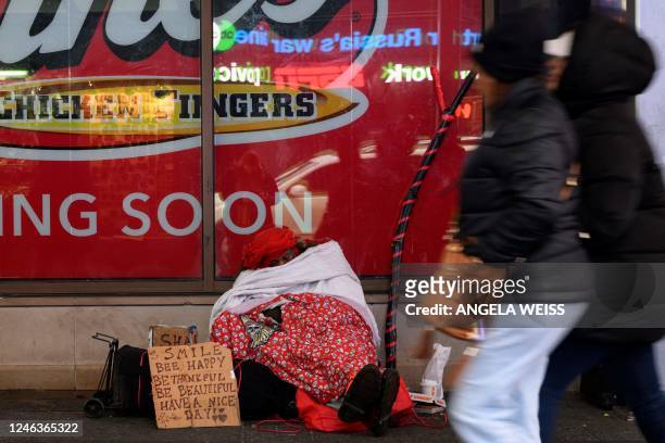 Homeless woman sits wrapped up in a blanket at Times Square during a rainy day on January 19, 2023 in New York City.