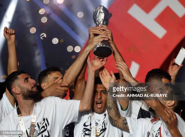 Iraq's national football team players celebrate with the trophy on the podium after winning the 25th Arabian Gulf Cup final football match against...