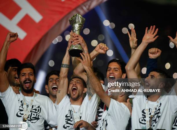 Iraq's national football team players celebrate with the trophy on the podium after winning the 25th Arabian Gulf Cup final football match against...