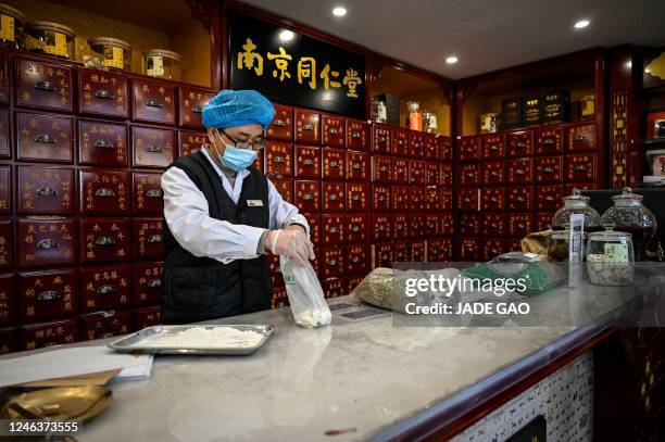 The photo taken on December 23, 2022 shows a medical employee working at a traditional Chinese medicine pharmacy in Beijing. - As Covid-19 rips...