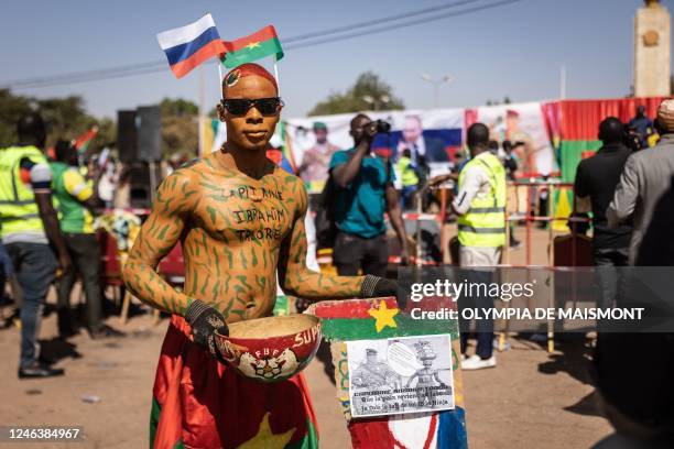 Man with camouflage bodypaint poses for a photograph during a protest to support the Burkina Faso President Captain Ibrahim Traore and to demand the...