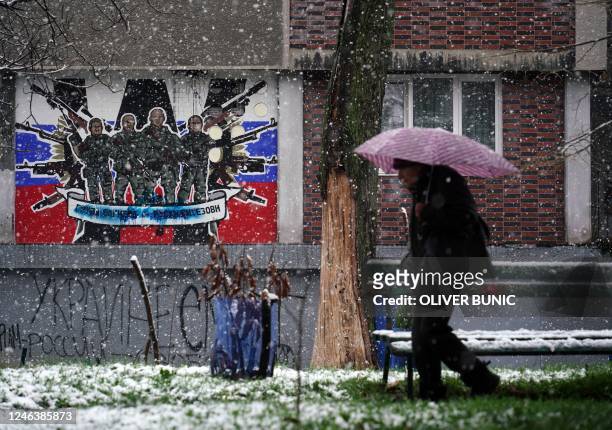Pedestrian walks past a defaced mural to the glory of Russia's mercenary group Wagner reading "Wagner Group - Russian knights" on the side wall of an...