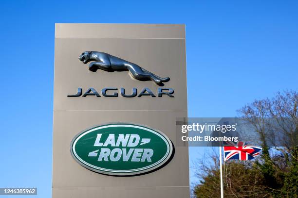 Totem displaying company logos next to a British union flag at the entrance to Tata Motors Ltd.'s Jaguar Land Rover vehicle manufacturing plant in...