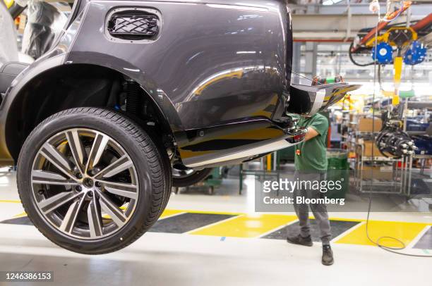 An employee fixes a part to the back of a Range Rover sports utility vehicle on the production line at Tata Motors Ltd.'s Jaguar Land Rover vehicle...