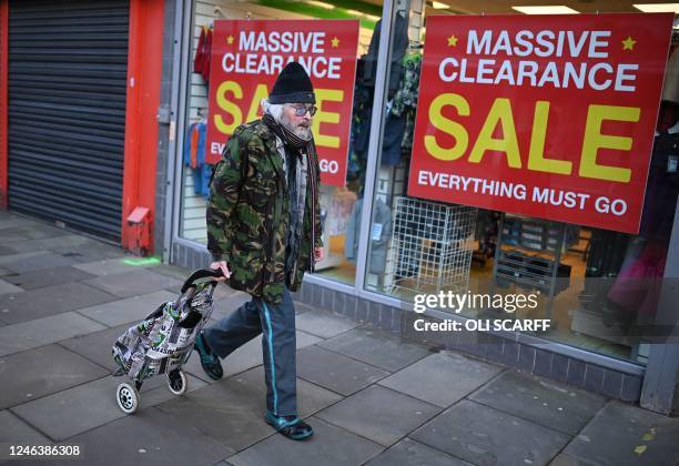 Pedestrian wheels a shopper past a shop advertising a closing-down sale in Bolton, north west England on January 20, 2023.