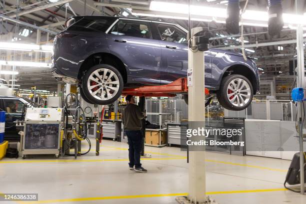 An employee works on the underside of a Range Rover sports utility vehicle at Tata Motors Ltd.'s Jaguar Land Rover vehicle manufacturing plant in...