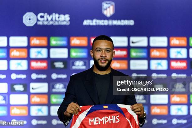 Newly signed Atletico Madrid's Dutch forward Memphis Depay poses for pictures holding his jersey during his official presentation at the Wanda...