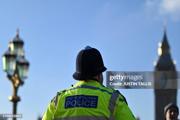 Metropolitan Police officer walks beside a protest march against the Islamic revolutionary Guard Corps near Big Ben and the Houses of Parliament in...