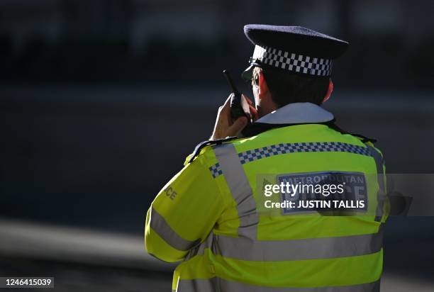 Metropolitan Police officer uses their radio during a protest march against the Islamic revolutionary Guard Corps , in central London, on January 21,...