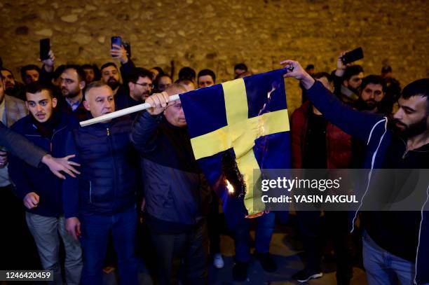 Protesters burn the national flag of Sweden as they demonstrate in front of the Consulate General of Sweden after Rasmus Paludan, leader of Danish...