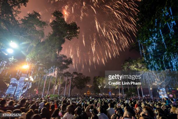 People watch a firework display to mark the Lunar New Year celebrations of the Year of the Cat in the Old Quarter on January 22, 2023 in Hanoi,...