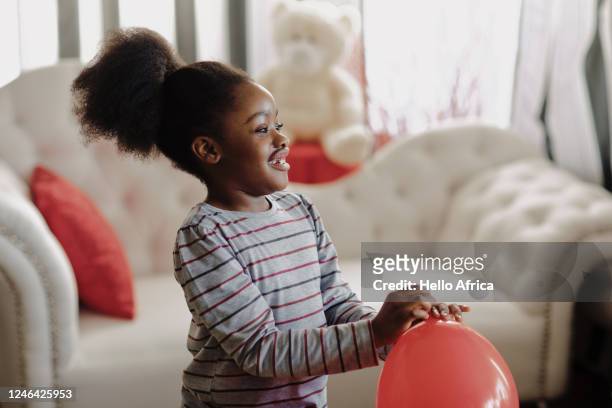 beautiful happy young girl smiling with a red balloon in her hand - balloon girl stock pictures, royalty-free photos & images