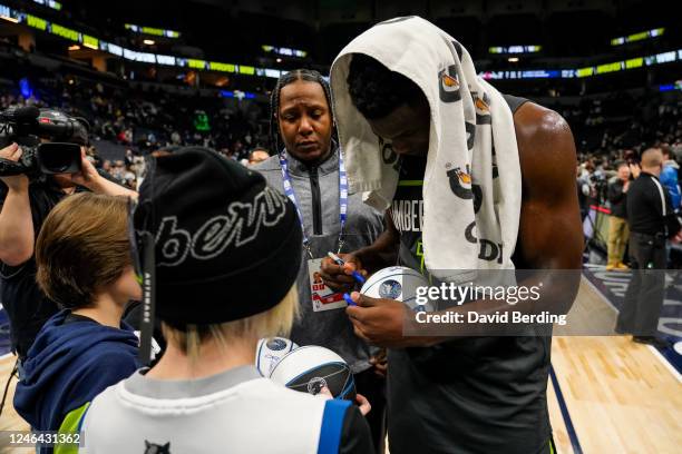 Anthony Edwards of the Minnesota Timberwolves signs autographs for fans as he walks off the court after the game against the Houston Rockets at...