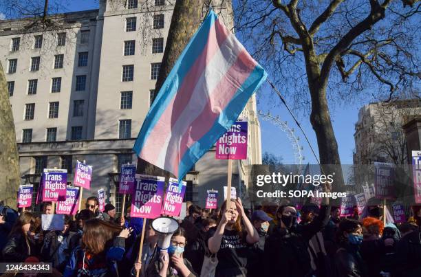 Protesters hold 'Trans rights now' placards and a trans pride flag during the demonstration. Protesters gathered outside Downing Street in support of...