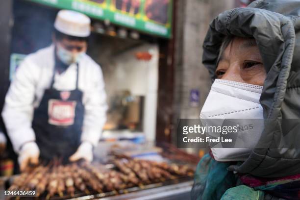 Women wears a protective mask as she walks on Qianmen Street ahead of Chinese New Year, the Year of the rabbit, on January 22, 2023 in Beijing,...