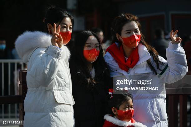 People wearing face masks with patterns of rabbits pose for a picture at the entrance of a park on the first day of Chinese Lunar New Year...