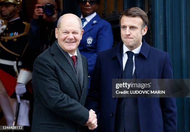 France's President Emmanuel Macron shakes hands with German Chancellor Olaf Scholz as they arrive to attend a ceremony as part of the celebration of...