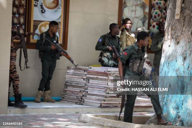 Police officers take up positions outside of the Mayor's office where an ongoing gun battle erupted following a reported explosion, in Mogadishu, on...