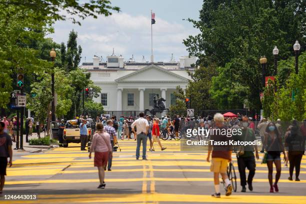 People walk down 16th street after volunteers, with permission from the city, painted "Black Lives Matter" on the street near the White House on June...