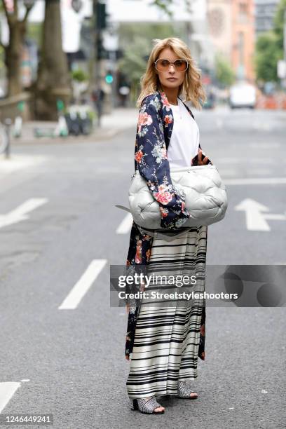 Influencer Gitta Banko, wearing black and white striped pants by Dries Van Noten, a long dark blue coat with multicolored floral print and sequin...