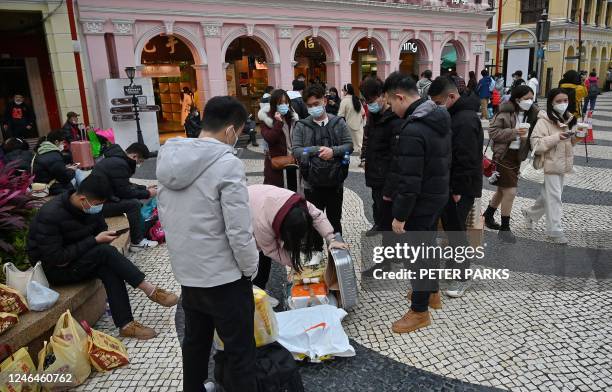 This photo taken on January 17, 2023 shows tourists from mainland China on the street with their suitcases in the southern Chinese enclave of Macau....