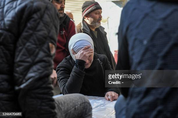 Mourner reacts as she sits by the box containing the body of one of the victims of a building which collapsed the day before in Syria's war-damaged...