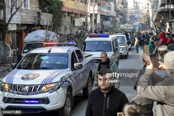 Police vehicles adorned with olive tree branches move in a funerary procession for the victims of a building which collapsed the day before in...