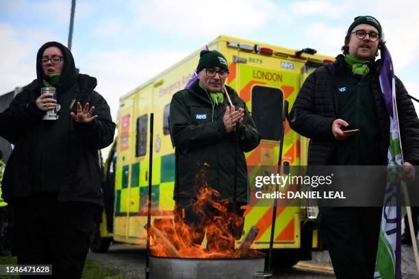 Ambulance workers warm themselves as they take part in a rally at a picket line outside the Docklands Emergency Operating Centre, Newham Dockside, in...