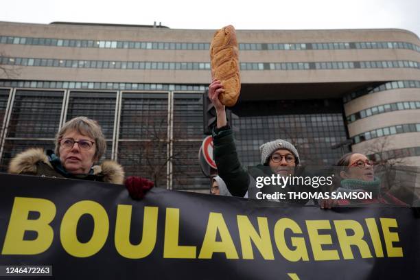 Woman holds a loaf of bread up as she stands behimd a sign that reads, 'bakery', during a protest organised by the collective for the survival of...