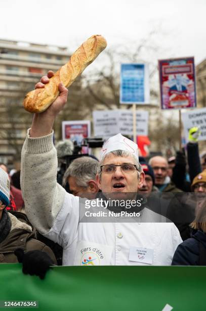 Demonstrator holds up a baguette during a demonstration in Paris on 23 January 2023, organised by the collective ''For the survival of bakeries and...