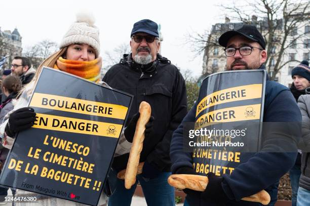 Demonstrators pose with bread sticks holding signs ''Bakery in danger, UNESCO the cemetery of the baguette'' during a demonstration in Paris on 23...