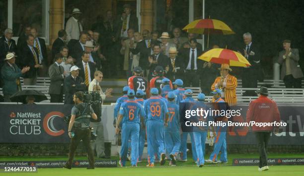 England batsmen Steven Finn and James Anderson leave the field followed by the India team as rain ends play in the 4th One Day International between...