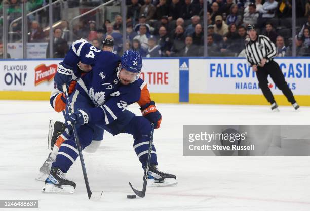 Toronto Maple Leafs center Auston Matthews fights through a check by New York Islanders defenseman Ryan Pulock to go to the net and score as the...