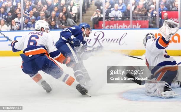Toronto Maple Leafs center Auston Matthews fights through a check by New York Islanders defenseman Ryan Pulock to go to the net and score on New York...