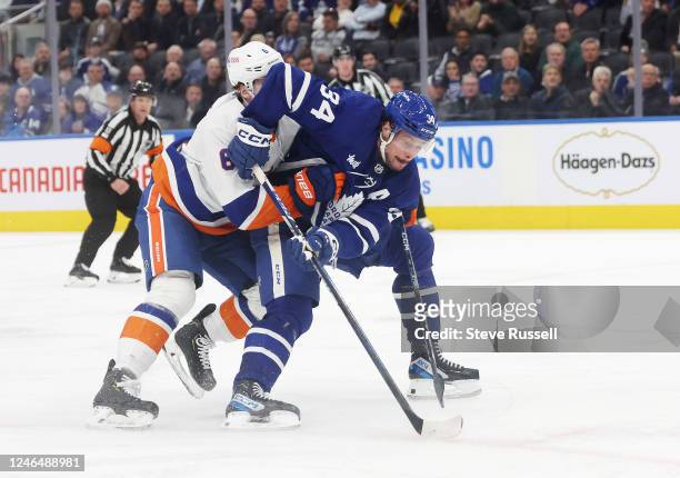 Toronto Maple Leafs center Auston Matthews fights through a check by New York Islanders defenseman Ryan Pulock to go to the net and score as the...