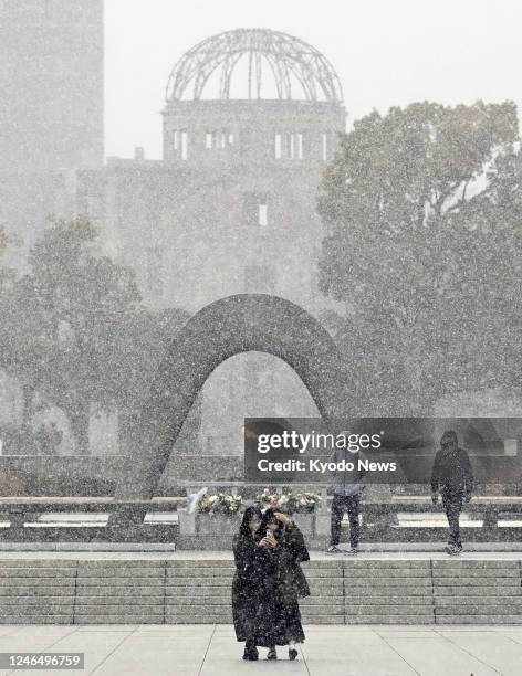 People visit the Peace Memorial Park in Hiroshima, western Japan, amid snow on Jan. 24, 2023. The Atomic Bomb Dome is seen in the background.