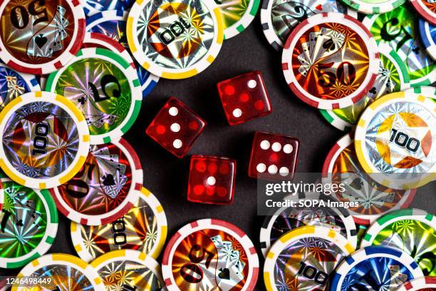 In this photo illustration, dice and casino tokens seen displayed on a table.