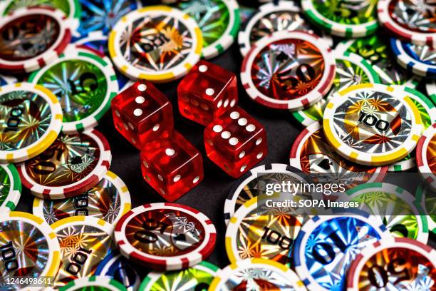 In this photo illustration, dice and casino tokens seen displayed on a table.