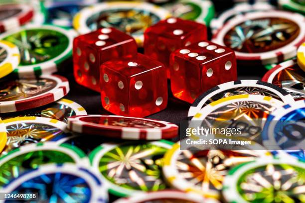 In this photo illustration, dice and casino tokens seen displayed on a table.