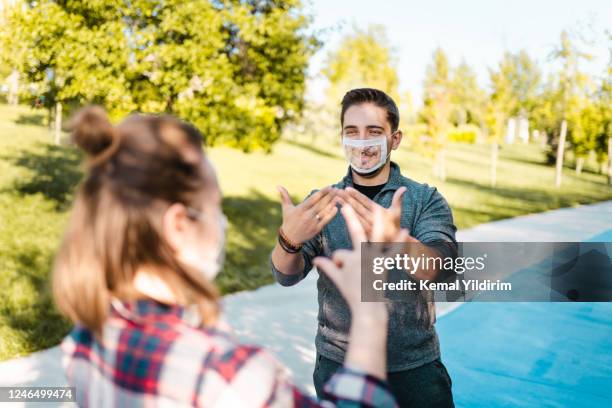 adultos jóvenes sordos sordos y de audición dura que usan mascarilla facial especial para leer los labios - american sign language fotografías e imágenes de stock